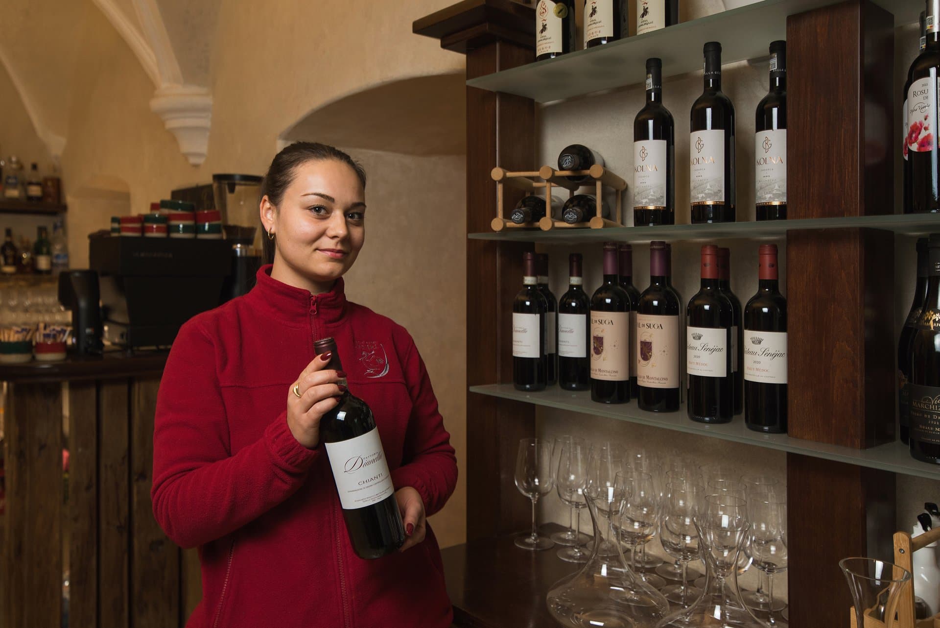 Membru al echipei de restaurant și servire prezentând o sticlă de vin din colecția castelului