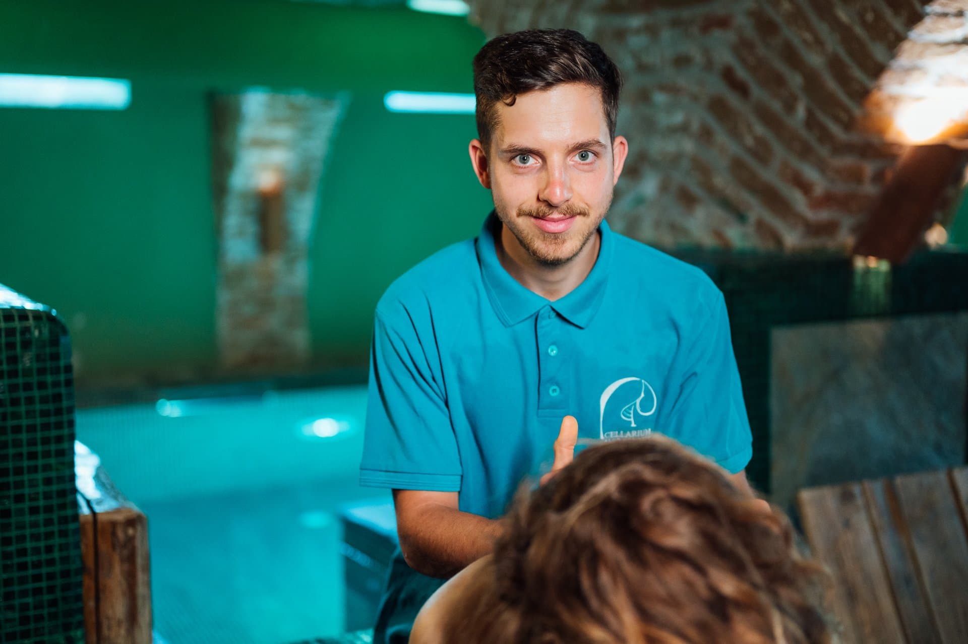 Membru al echipei spa ținând prosoape turcoaz în Tepidarium, la Cellarium Slow Down Spa